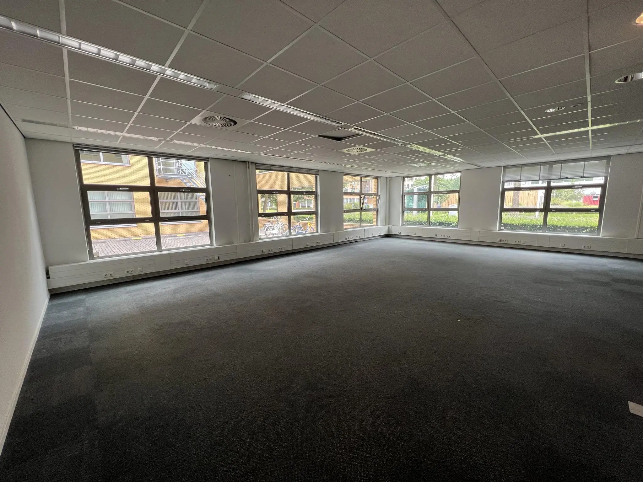 Leeg kantoorruimte met tapijtvloer en grote ramen aan de Rivium 2e Straat.